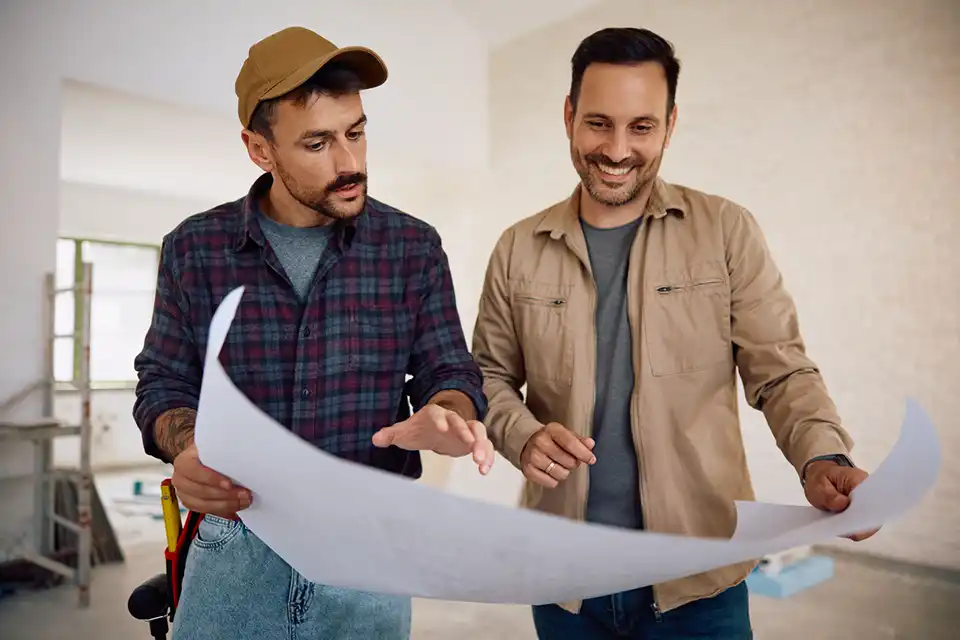 a contractor showing build plans to a smiling homeowner